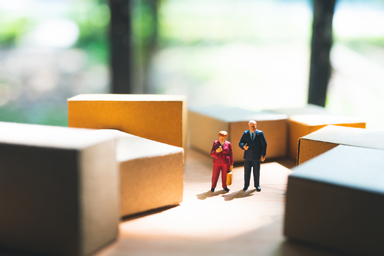 Two miniature logistics managers surrounded by boxes