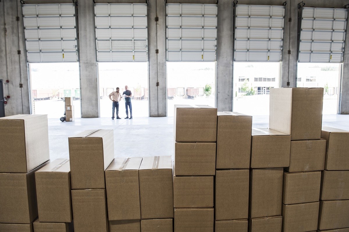 Team of workers check out inventory in front of loading dock doors in a new warehouse.