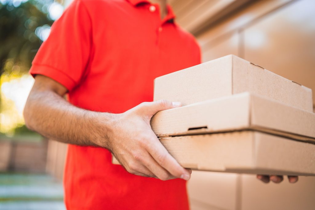 Delivery man carrying packages while making home delivery.